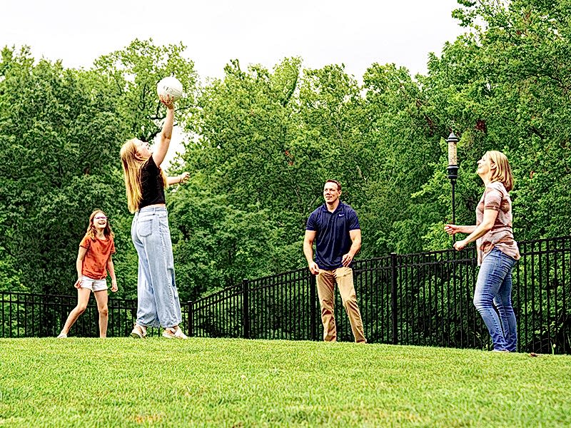 About Us Feature 3 Family playing volleyball in fenced in yard