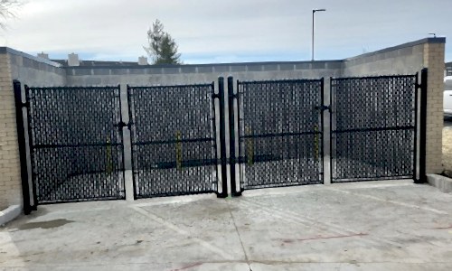 Large commercial dumpster enclosure with chain link gate