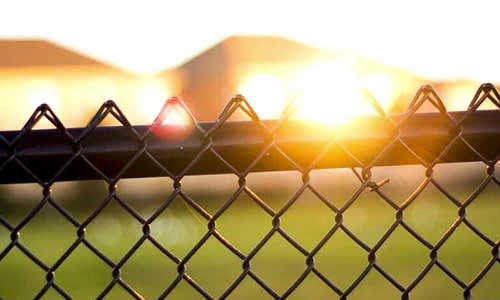 Fence Materials – Chain-Link Chain-link fence with sunset in the background